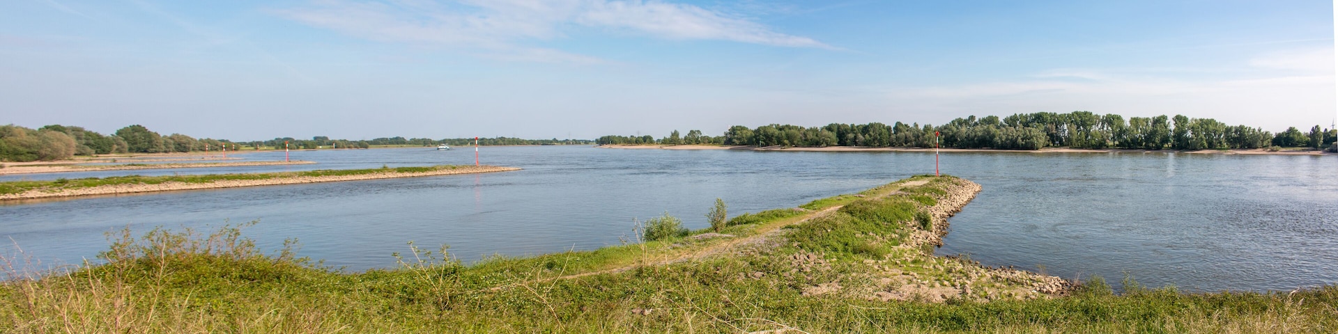 A river with a narrow strip of land on one side and a forest on the other.