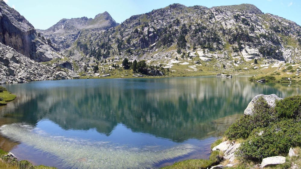 A mountain lake surrounded by rocky terrain and sparse vegetation.