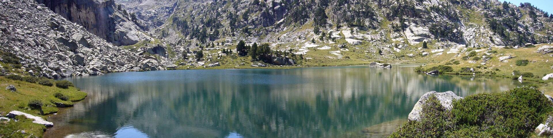 A mountain lake surrounded by rocky terrain and sparse vegetation.