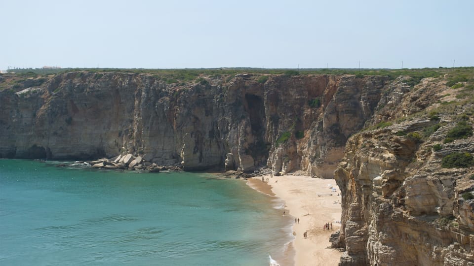A coastal cliff with a sandy beach and turquoise waters.