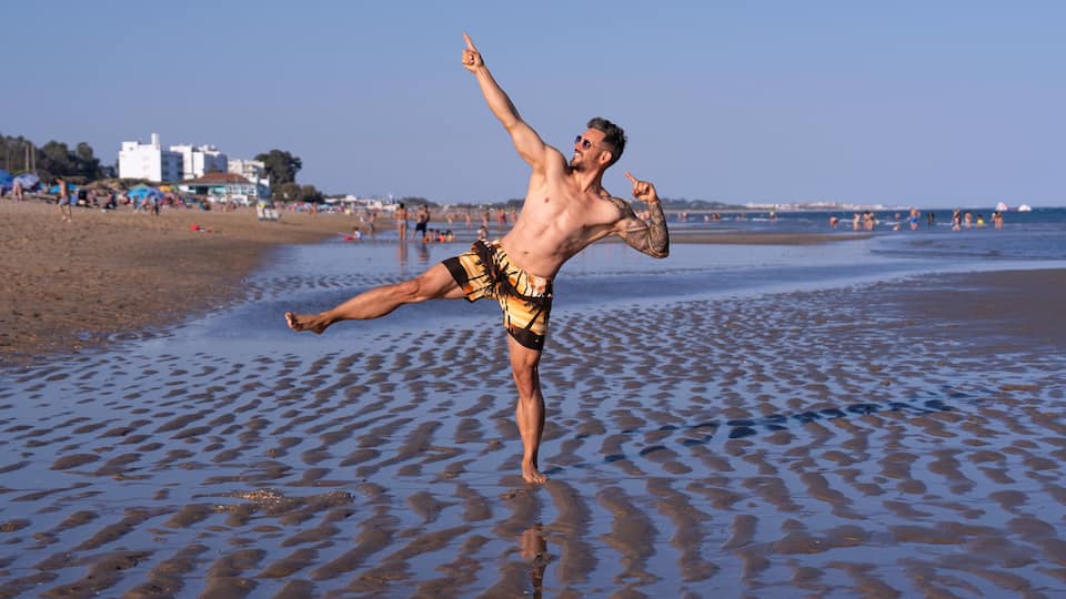 A beach with a person performing a kick.