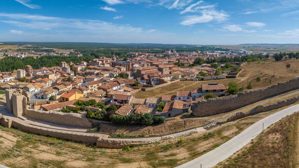 Aerial view of Almazan city walls, fortified gate, battlements above the Ebro river in Spain with cloudy blue sky