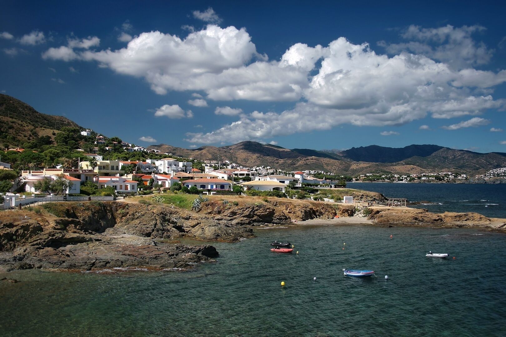 A coastal town with buildings on a hillside, clear blue water, and boats.