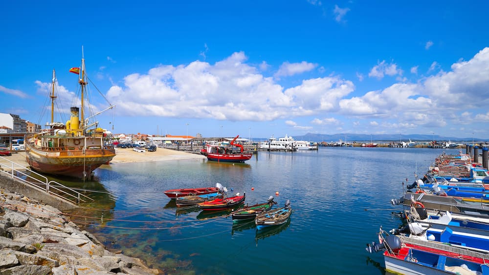 Un port où des bateaux sont amarrés le long de la côte, une plage de sable et un ciel bleu dégagé.
