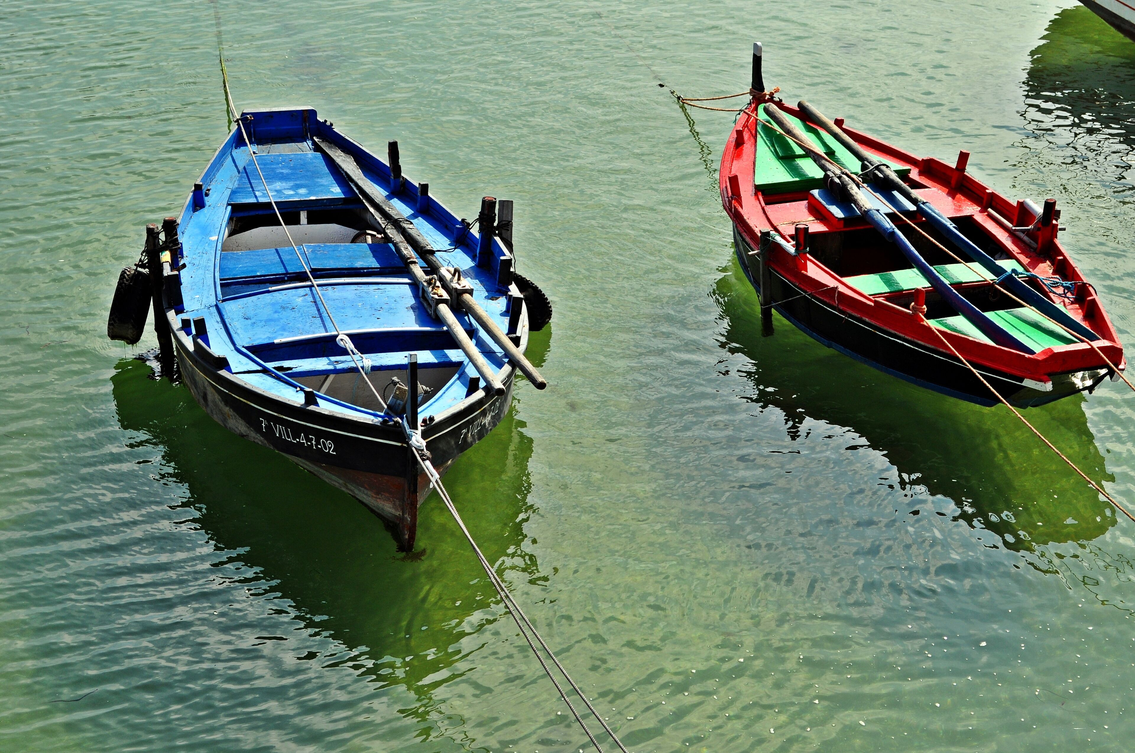 Two boats tied to a dock in clear water.