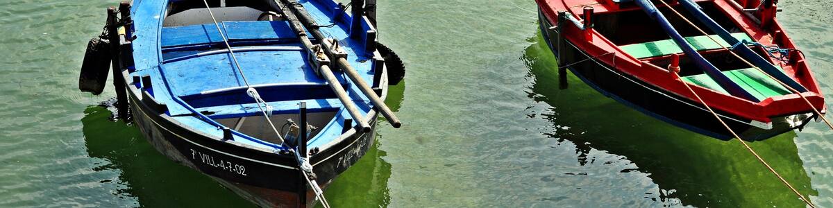 Two boats tied to a dock in clear water.