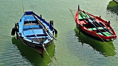 Dois barcos amarrados a um cais em águas calmas.