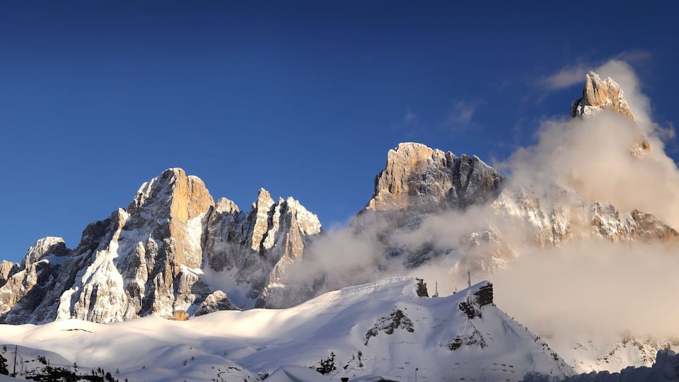 Snow-covered mountains with sharp peaks and a clear blue sky.
