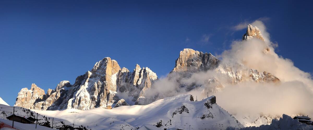 Snow-covered mountains with sharp peaks and a clear blue sky.