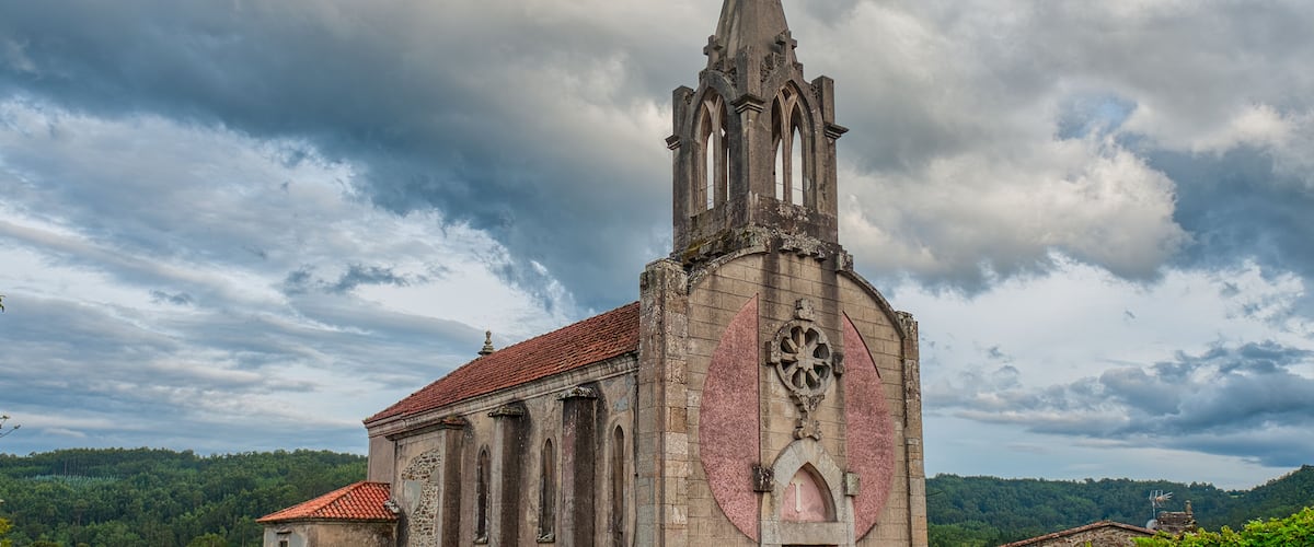 A historic church with a tall spire and a large circular window.