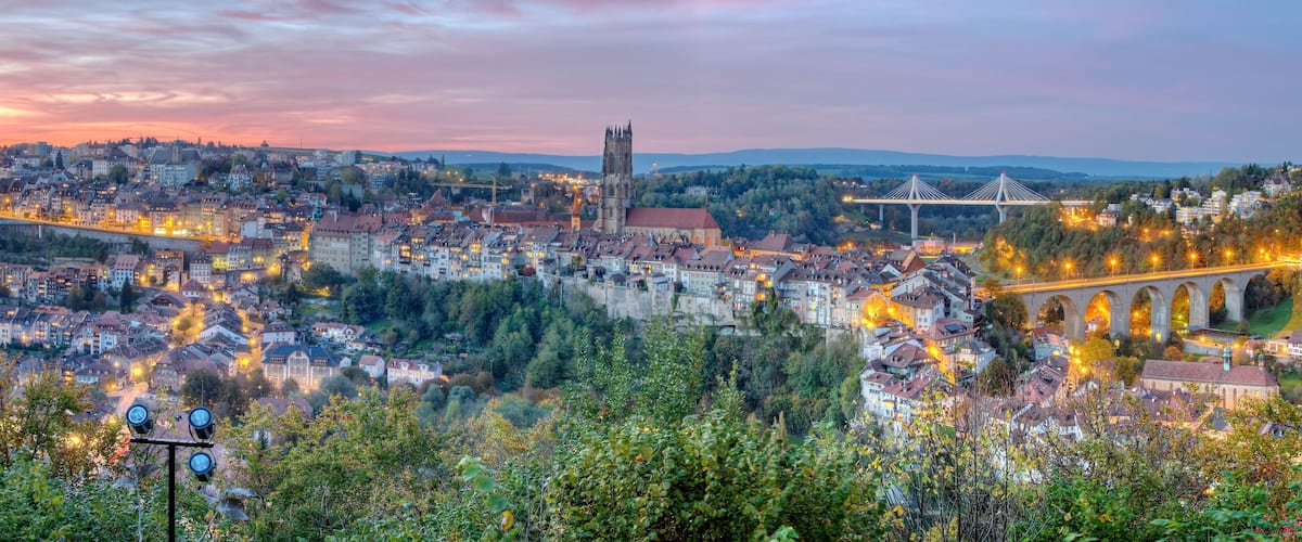 A panoramic view of a city with a prominent church, a bridge, and a river.