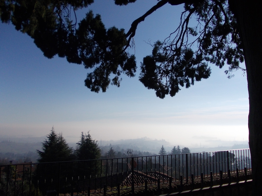 Paesaggio montuoso con cielo sereno, una recinzione e alberi.