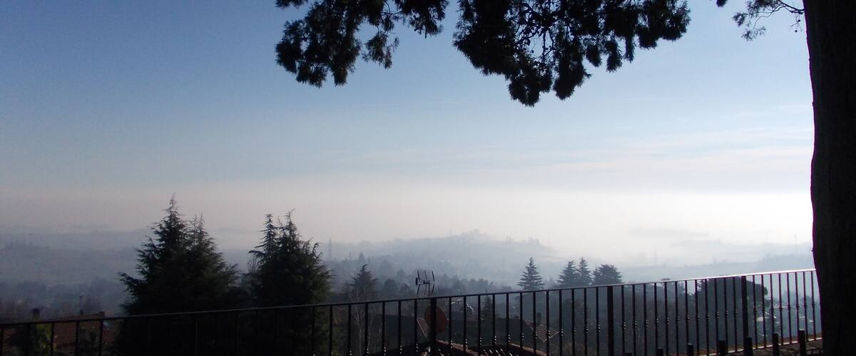 A mountainous landscape with a clear sky, a fence, and trees.
