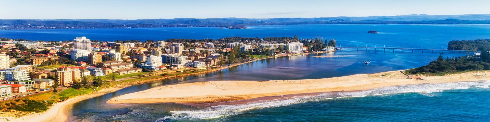A coastal city with a beach, a bridge, and a large body of water.