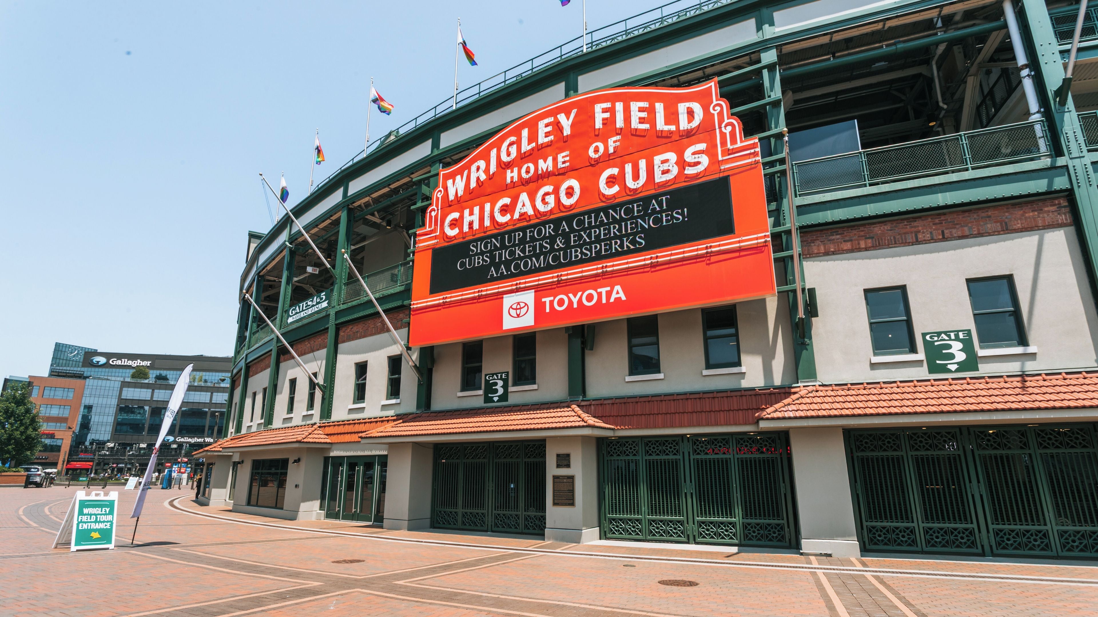 Wrigley Field, home of the Chicago Cubs, with a large sign and flags.