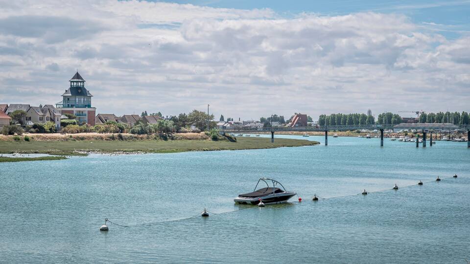 A river with boats, a bridge, and buildings in the background.