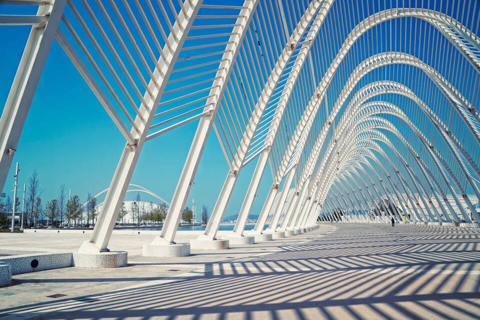 Uma ponte moderna com arcos brancos e um céu azul límpido.