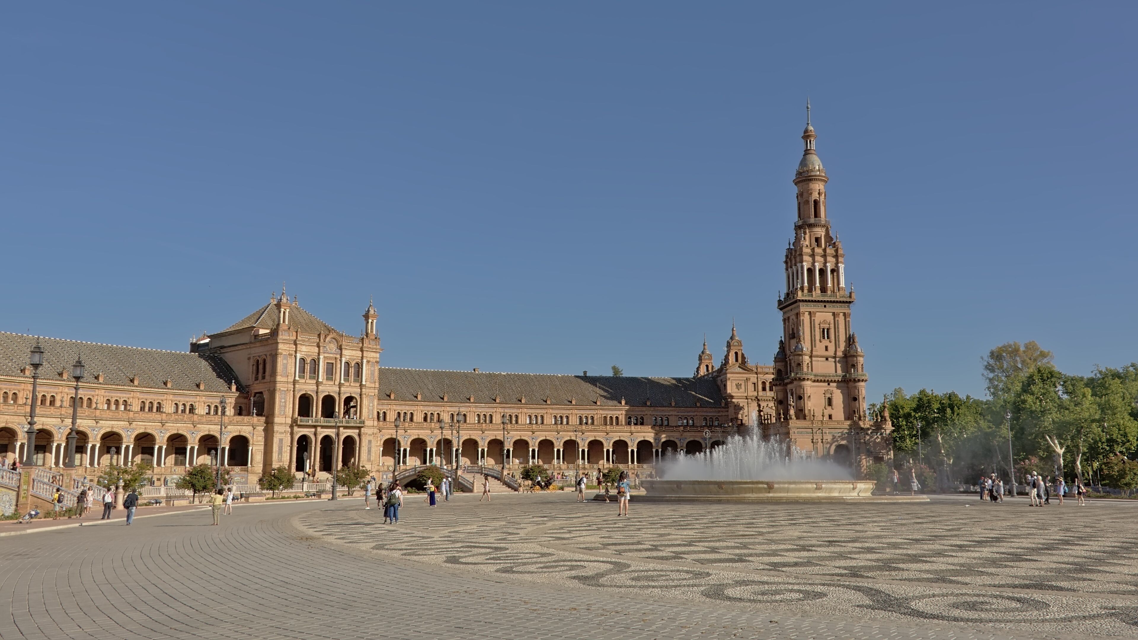 A historic building with a prominent tower and a fountain in the foreground.