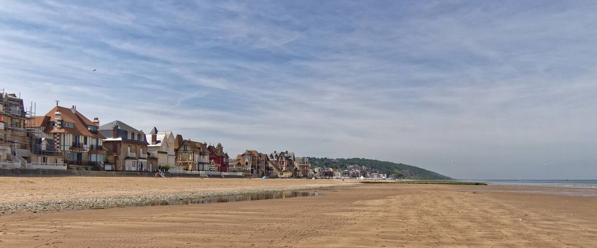 A beach with a row of colorful houses and a calm sea.