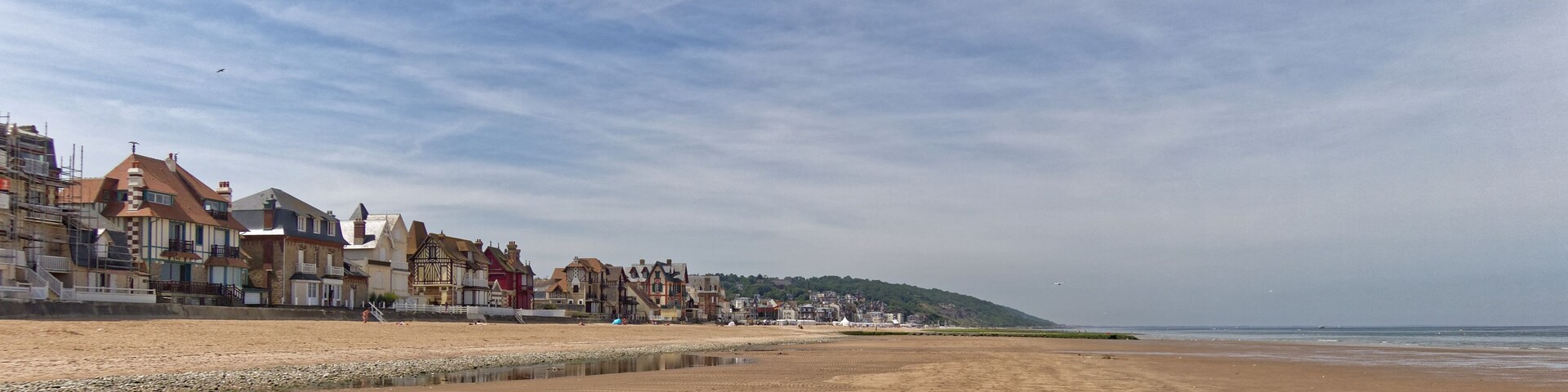 A beach with a row of colorful houses and a calm sea.