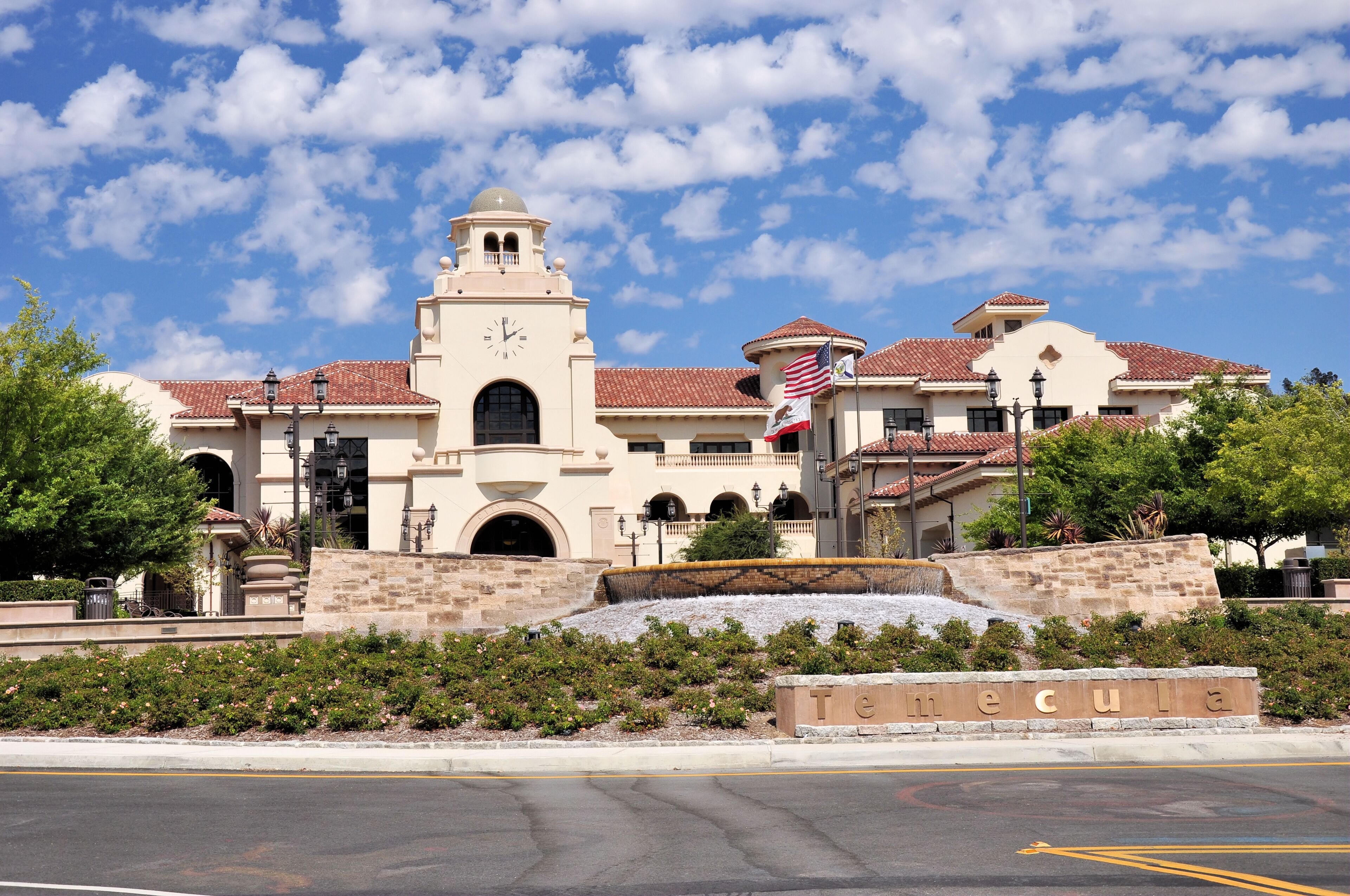 A historic building with a clock tower, surrounded by a landscaped area with a fountain and a sign reading 'Temecula.'