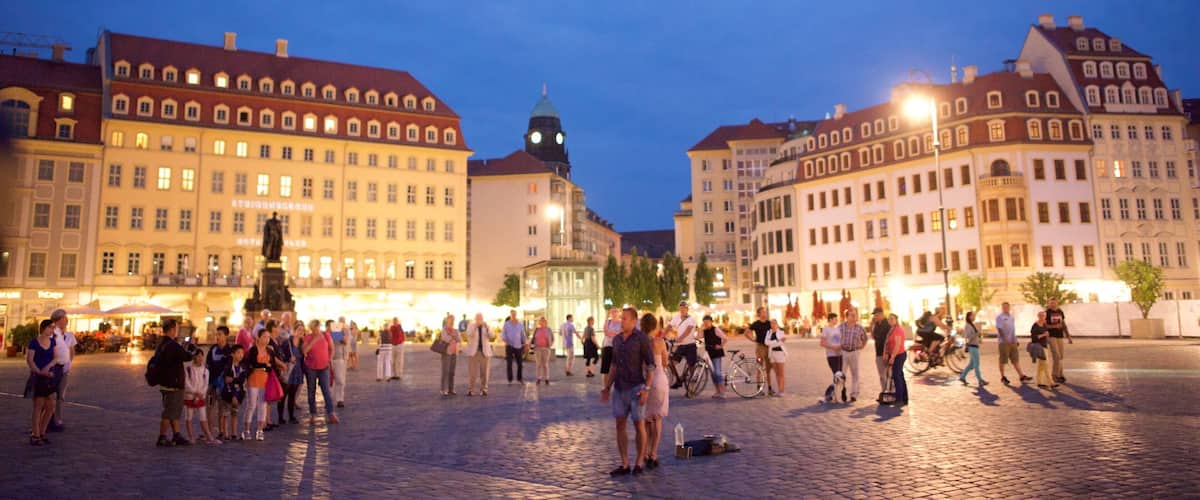 A historic square with cobblestone pavement, surrounded by classical European architecture and a prominent clock tower.
