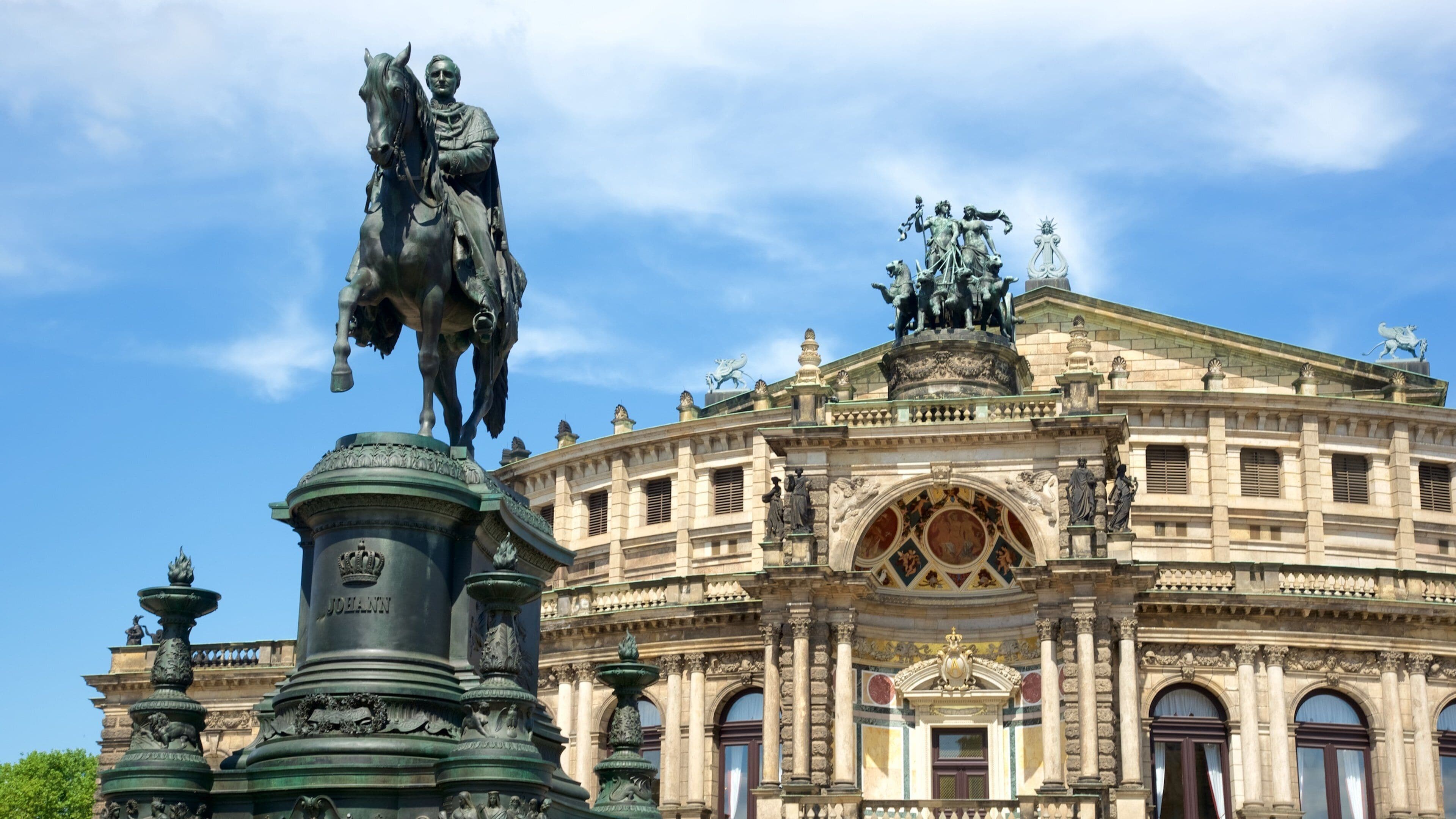 A statue of a man on horseback in front of a grand building with ornate architecture.