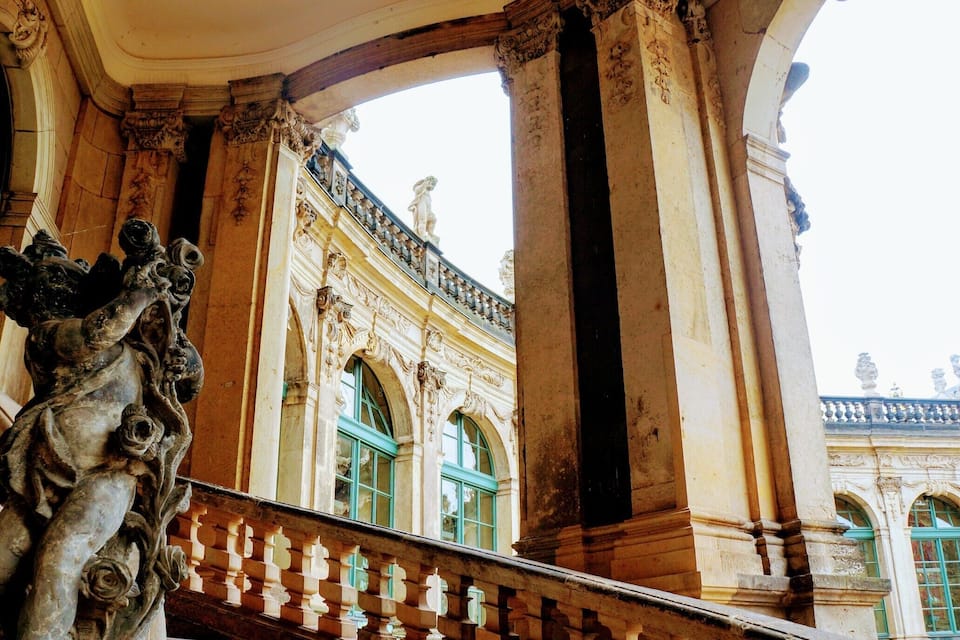 Ein prachtvolles Gebäude mit verzierten Säulen und einem Balkon mit einer Statue.
