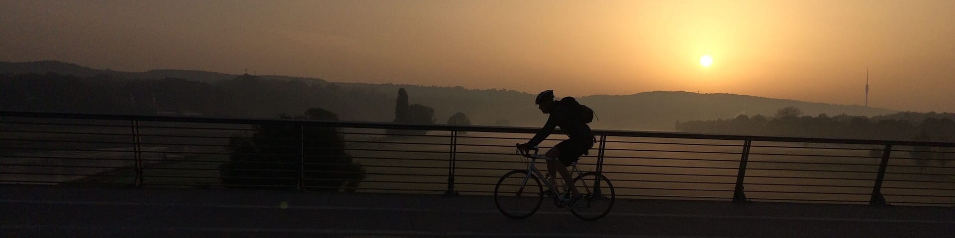 A silhouette of a person riding a bicycle during sunset.