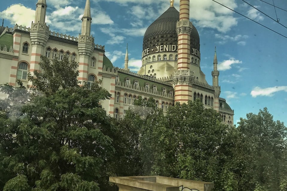 Ein historisches Gebäude mit einer markanten Kuppel und Türmen, umgeben von Bäumen.