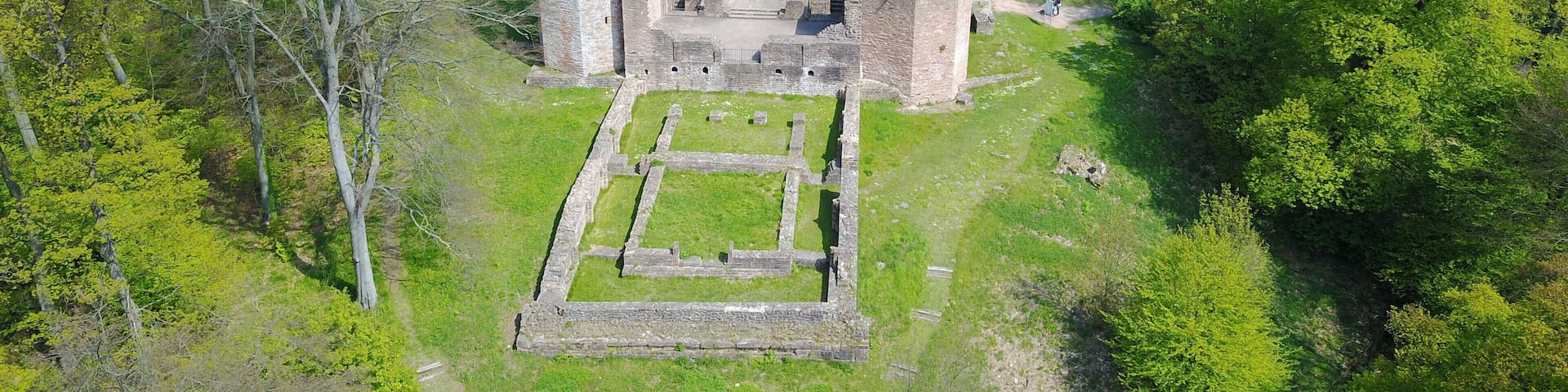 An aerial view of an ancient stone fortress surrounded by lush green trees.