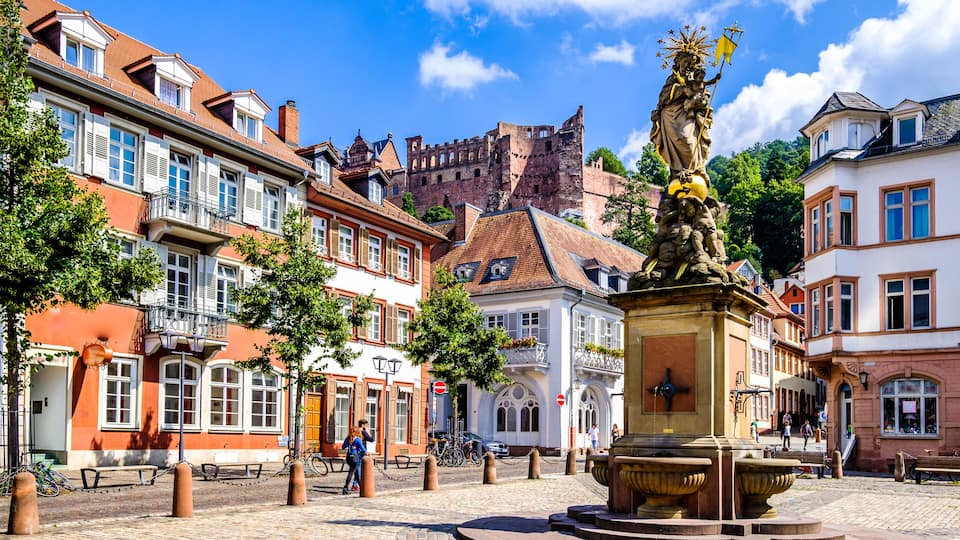 A historic square with a statue, cobblestone streets, and traditional European architecture.