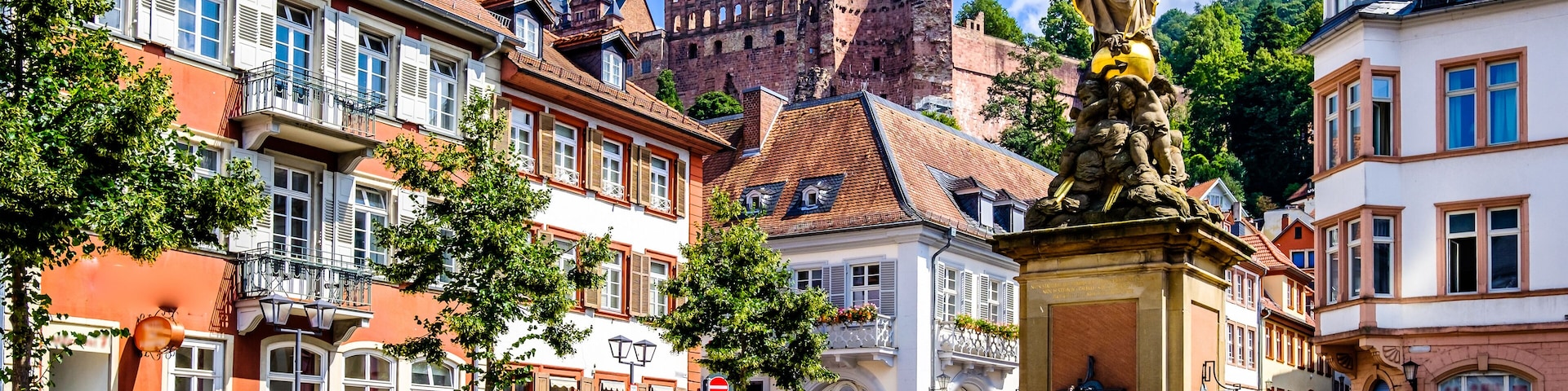 A historic square with a statue, cobblestone streets, and traditional European architecture.
