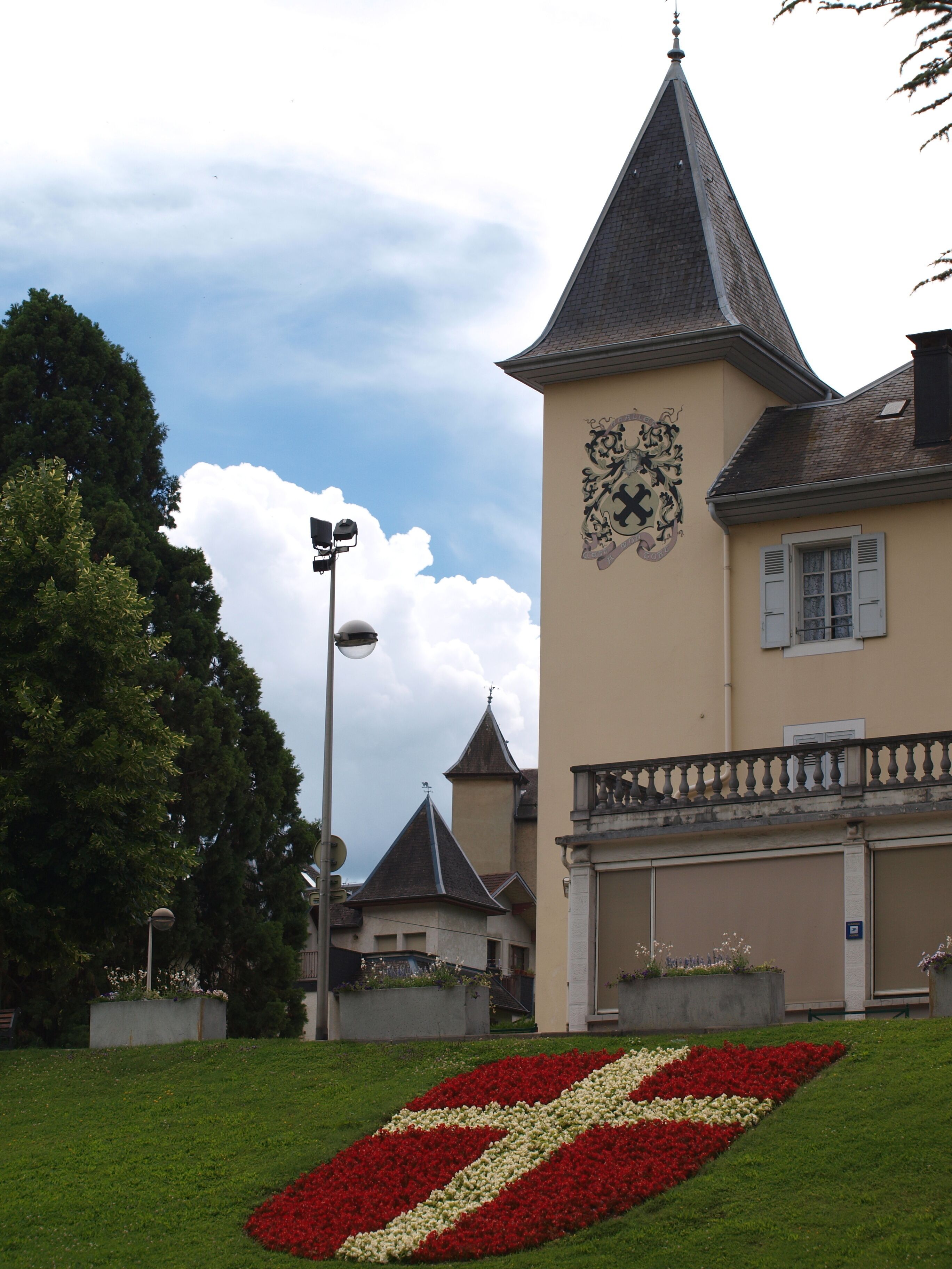 A building with a clock tower and a red and white flower bed in front.