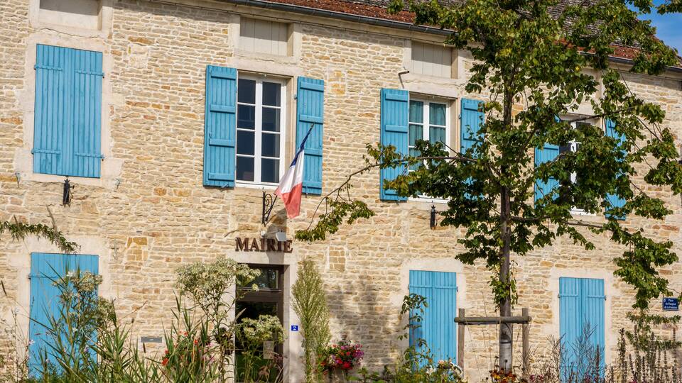 A stone building with blue shutters and a sign reading "MAIRIE".