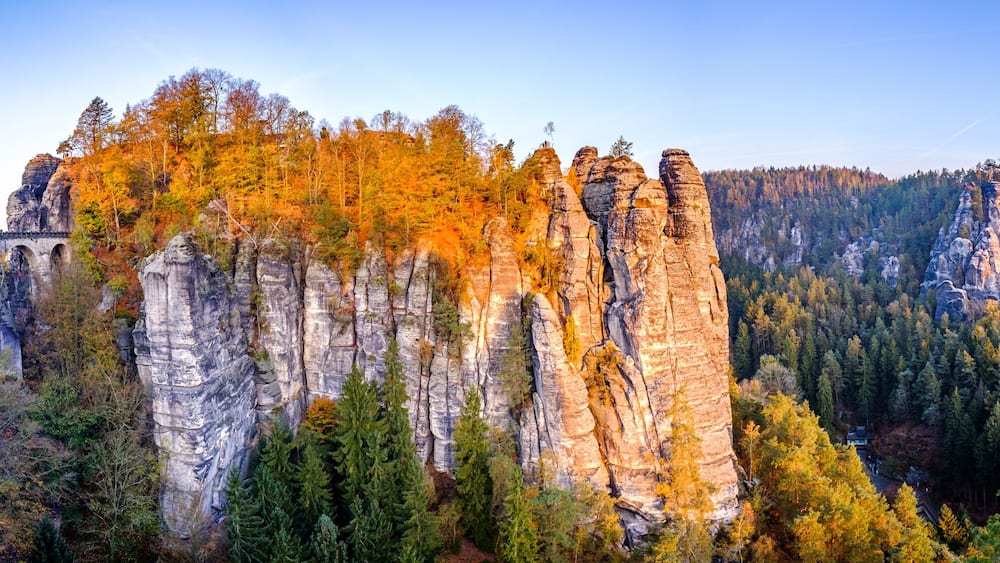 Eine bewaldete Landschaft mit markanten Felsformationen und einer Brücke.