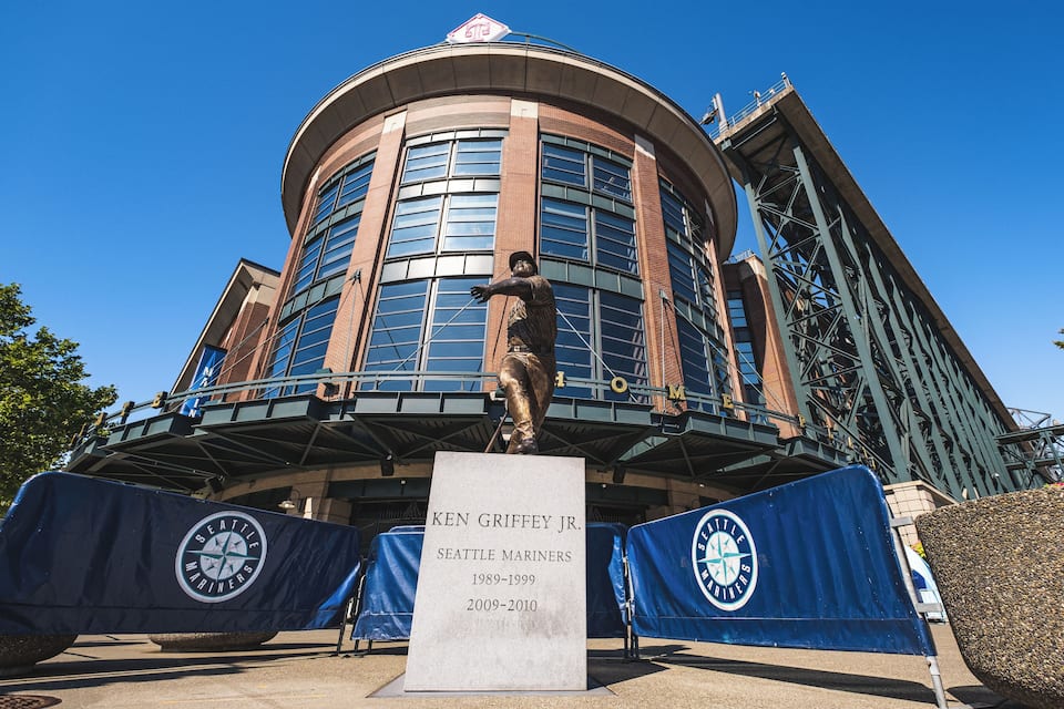 A baseball stadium with a statue of Ken Griffey Jr. and the Seattle Mariners logo.