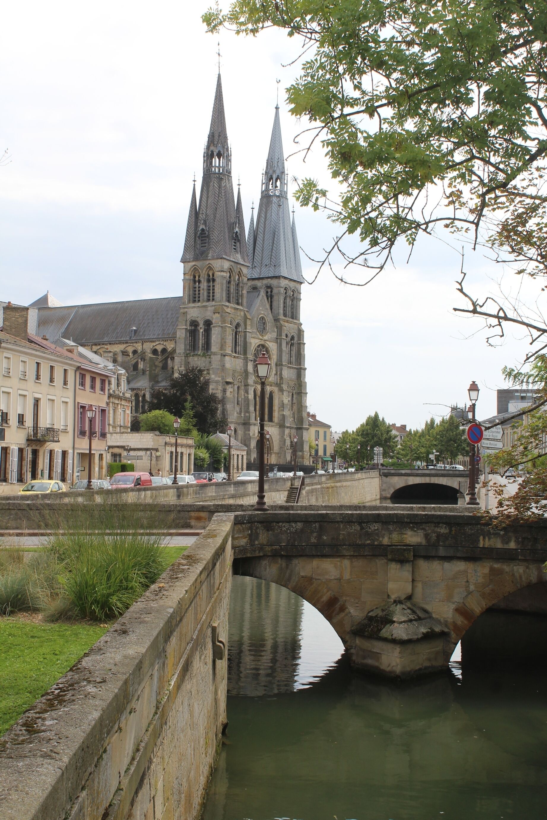 A stone bridge over a river, a historic church with twin spires, and surrounding buildings.