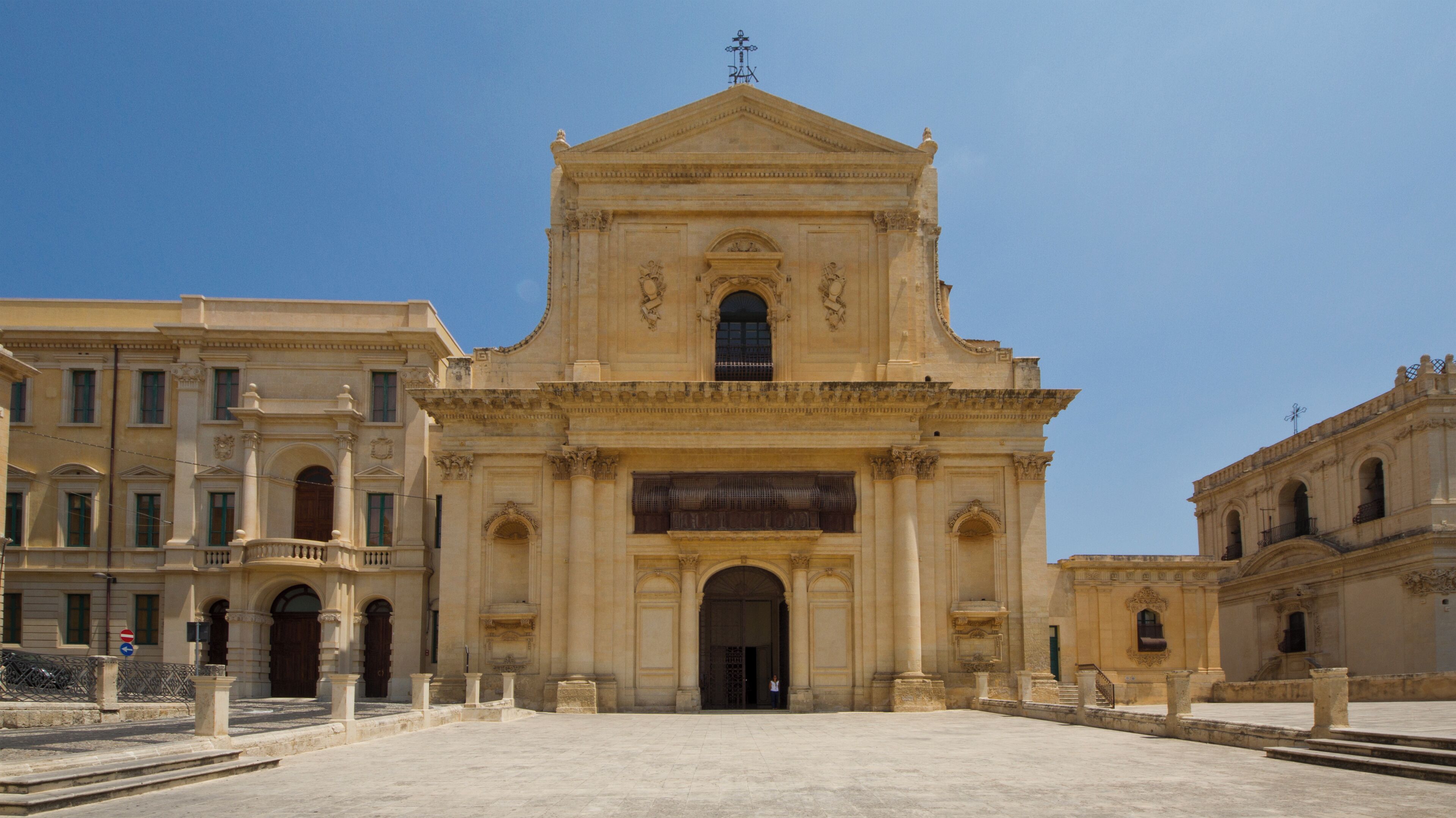 A historic church with a central dome and arched windows, flanked by classical buildings.