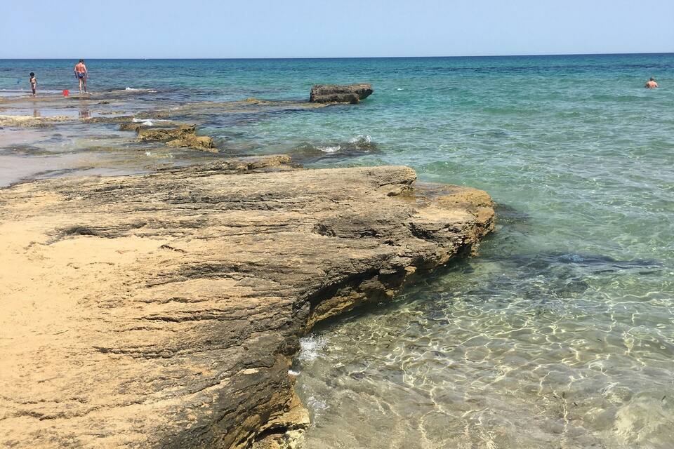 Una costa rocosa con aguas cristalinas y una vista distante del mar.
