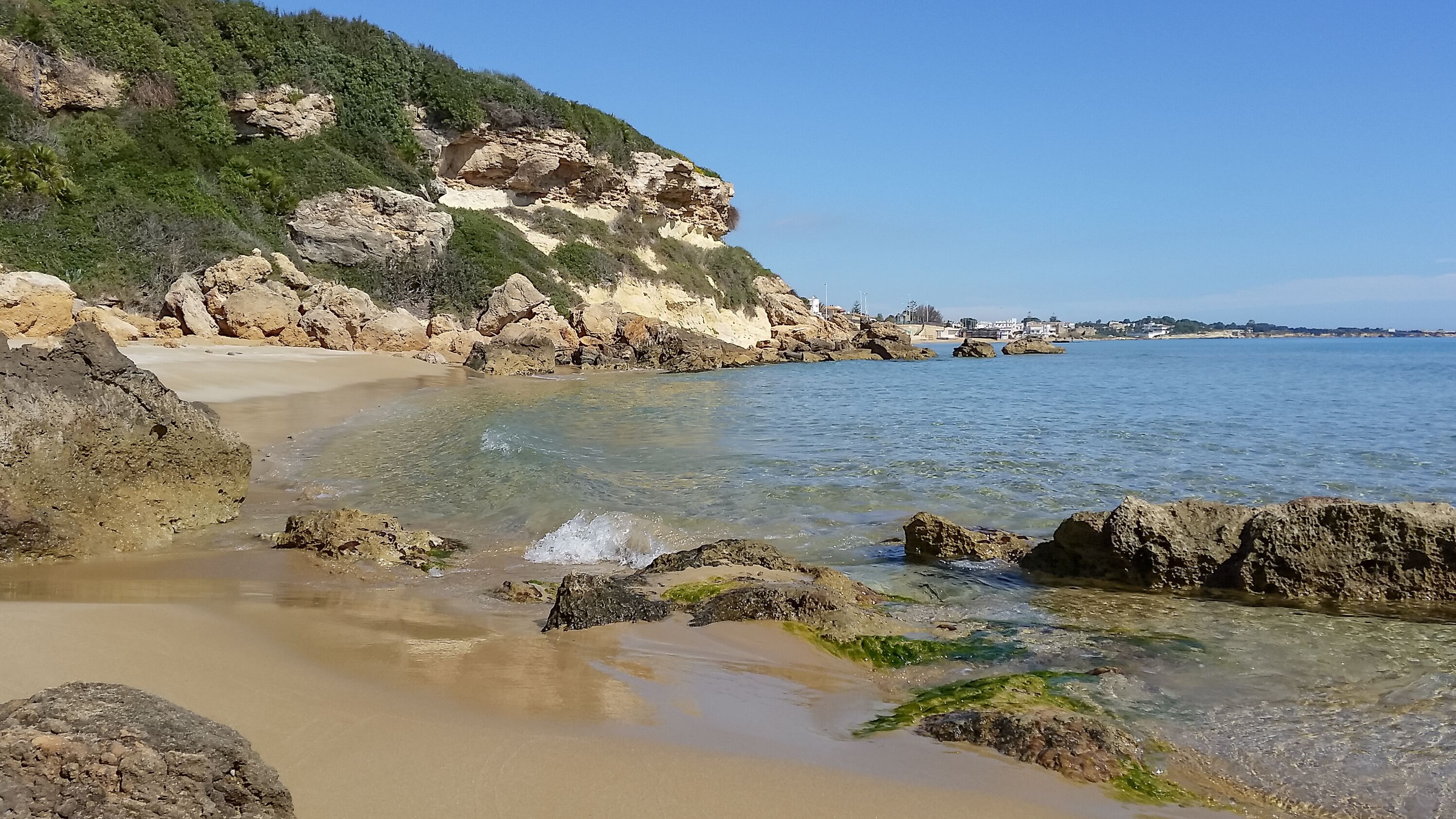 Un paisaje costero con aguas cristalinas, costas rocosas y una playa arenosa.