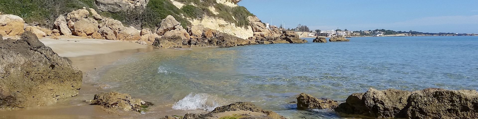 Un paisaje costero con aguas cristalinas, costas rocosas y una playa arenosa.