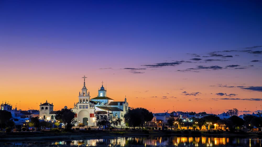 Une vue sur une ville au crépuscule, avec une église imposante et une riviÚre paisible qui reflÚte les bùtiments.