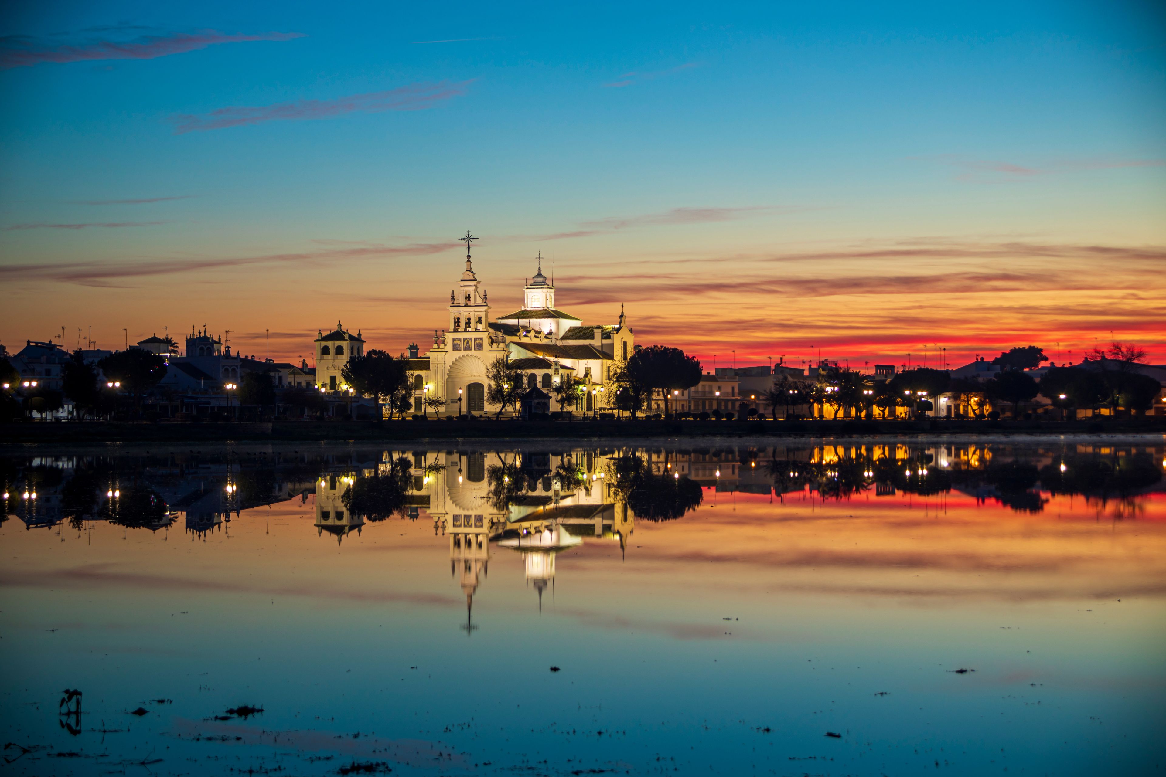 Landscape at dawn of the village and hermitage of El Rocío in Huelva, Spain, reflected in the calm waters of a lake