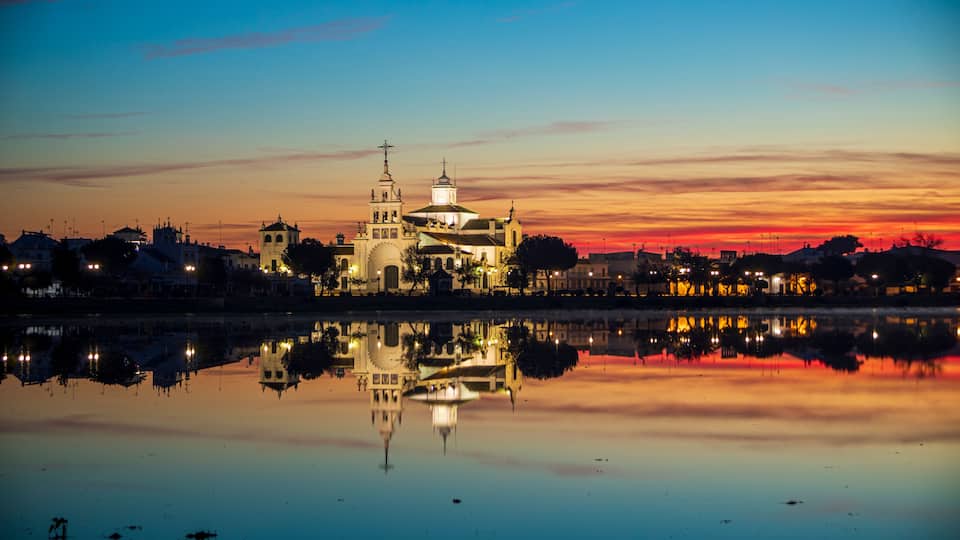 A cathedral reflected in calm water during twilight with a sunset sky.