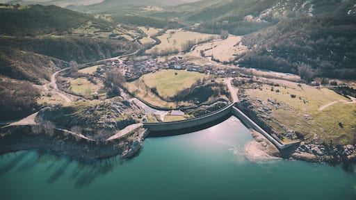 Un barrage, une rivière et un village entouré de collines.