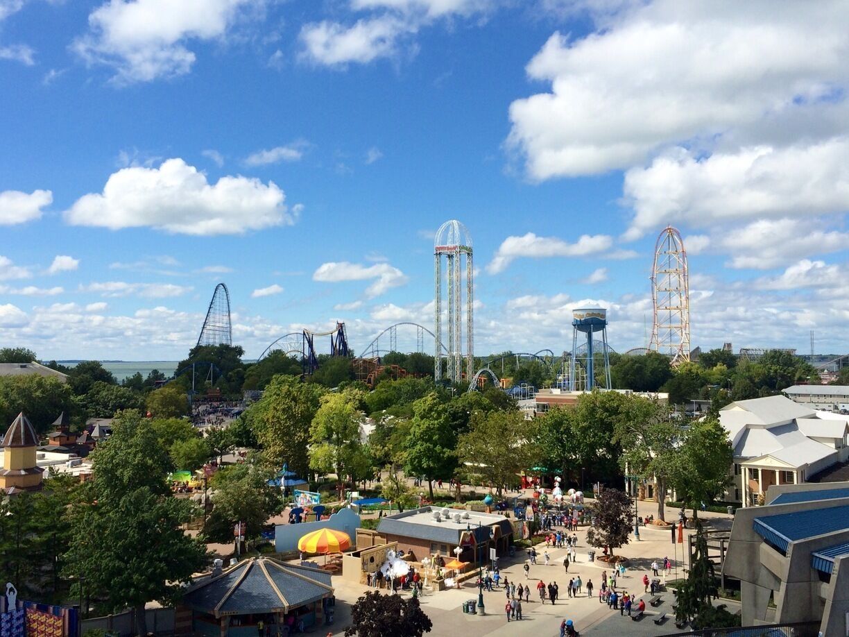 A theme park with roller coasters, water towers, and a large crowd.