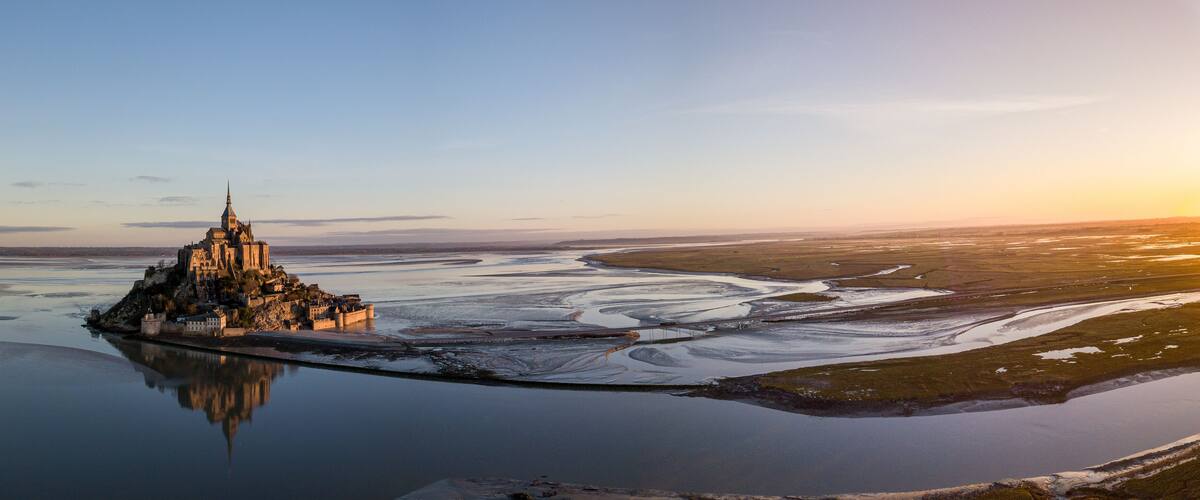 A castle on a small island surrounded by a large body of water.