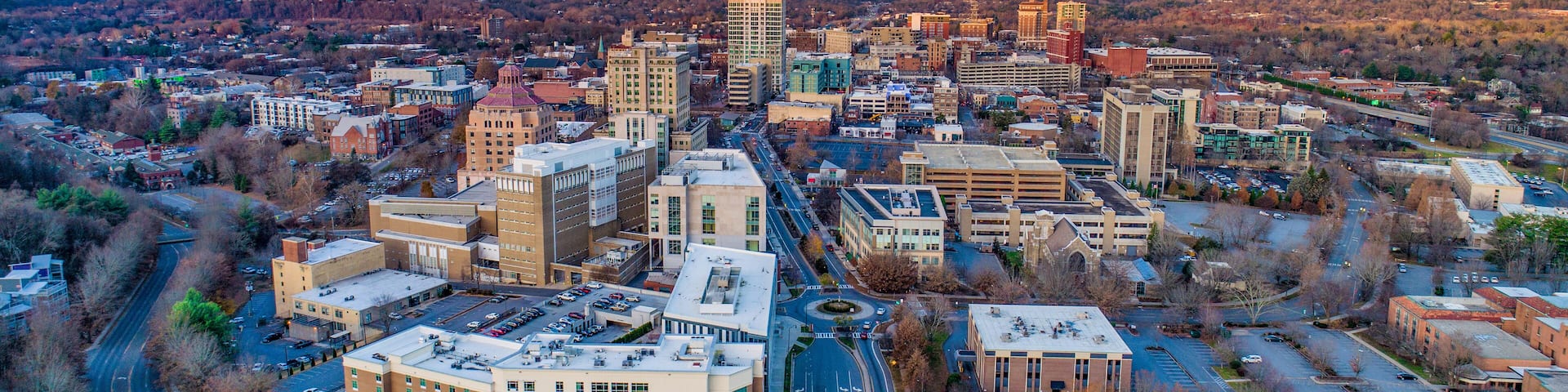A cityscape with a prominent building with a red roof, surrounded by other buildings and roads.