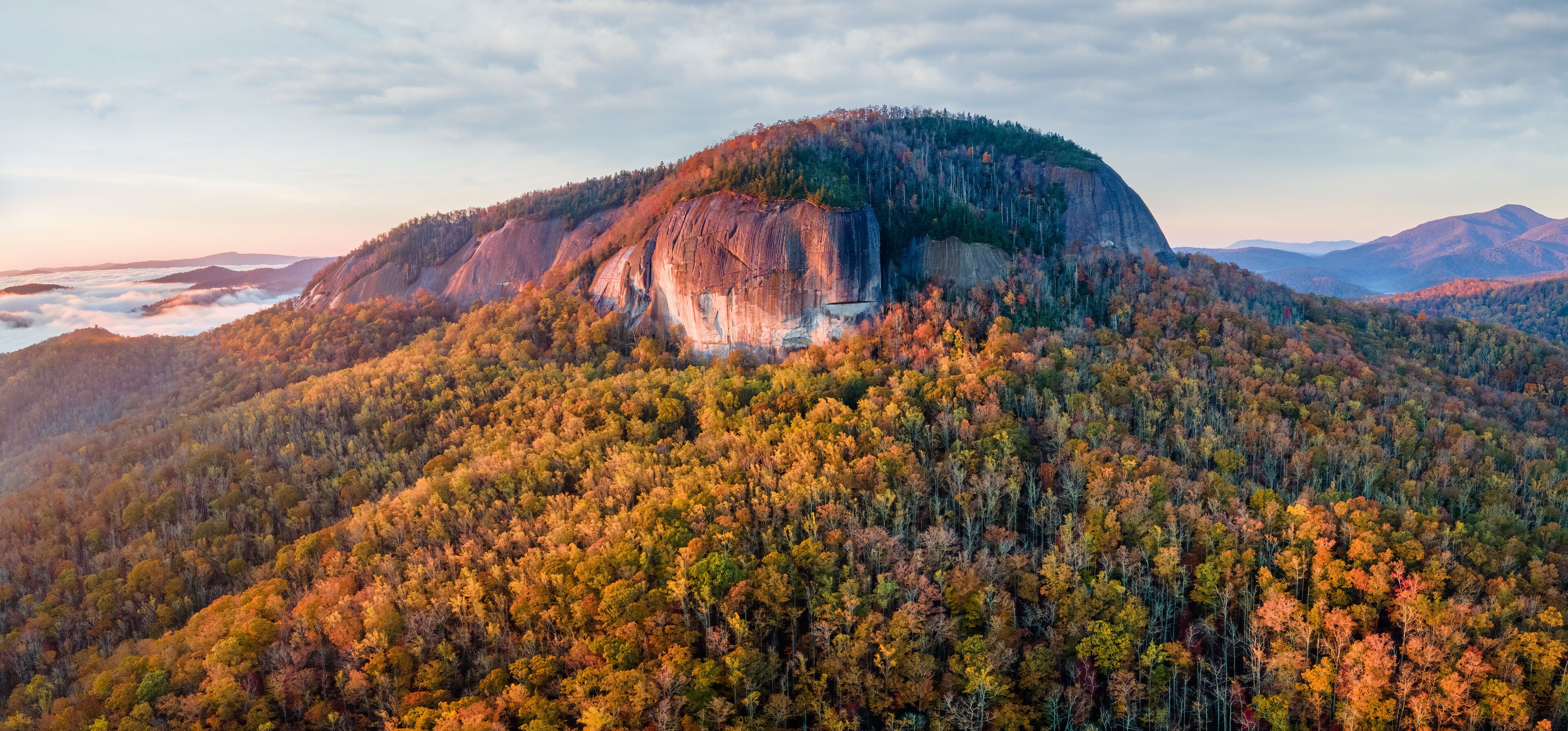 A forested mountain with a prominent rock formation.